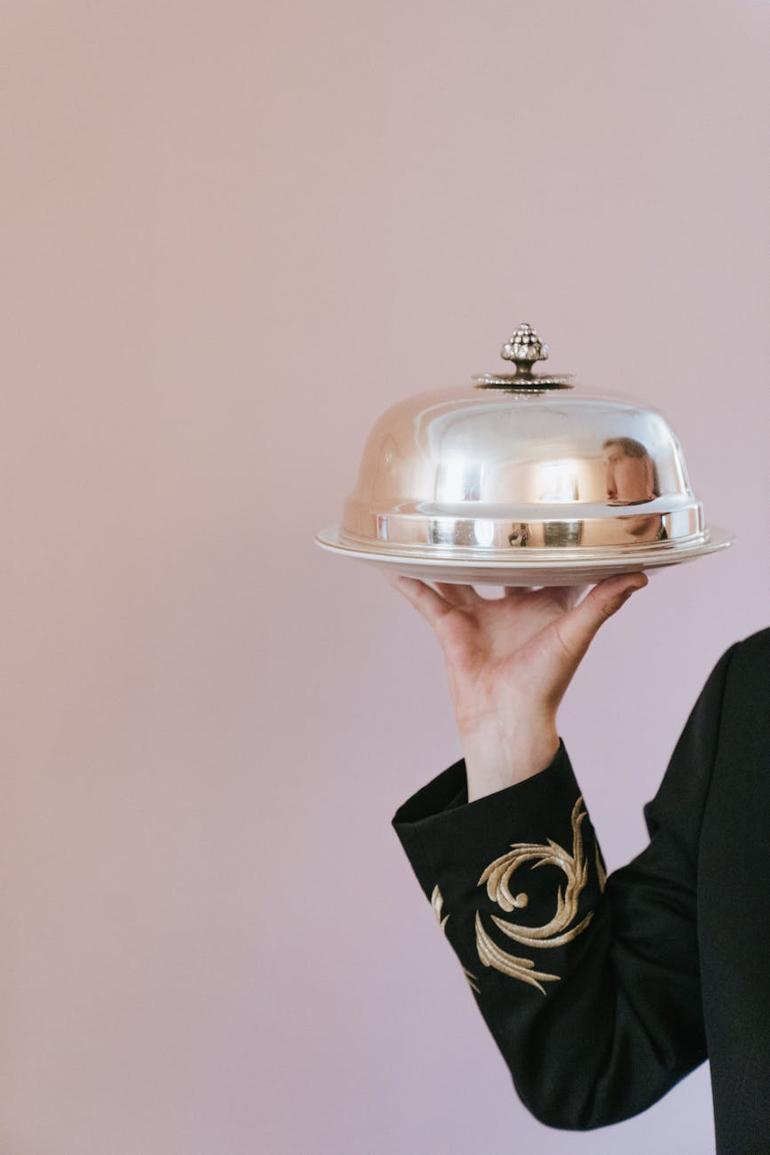 close up of waiter holding tray with silver cover
